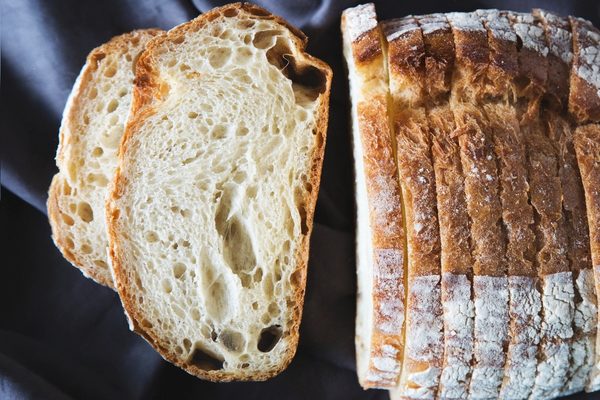 A sliced country loaf on a dark cloth.