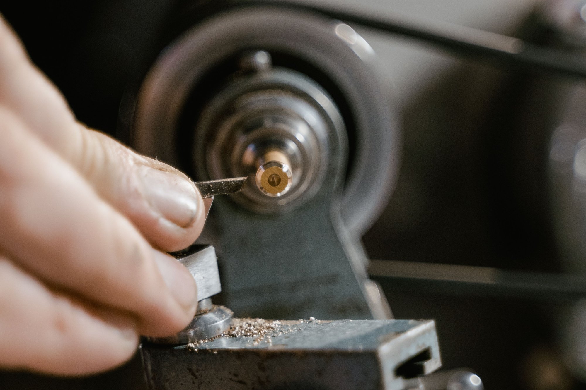 A locksmith&rsquo;s hands guiding a key blank through the cutting wheel of a key machine.