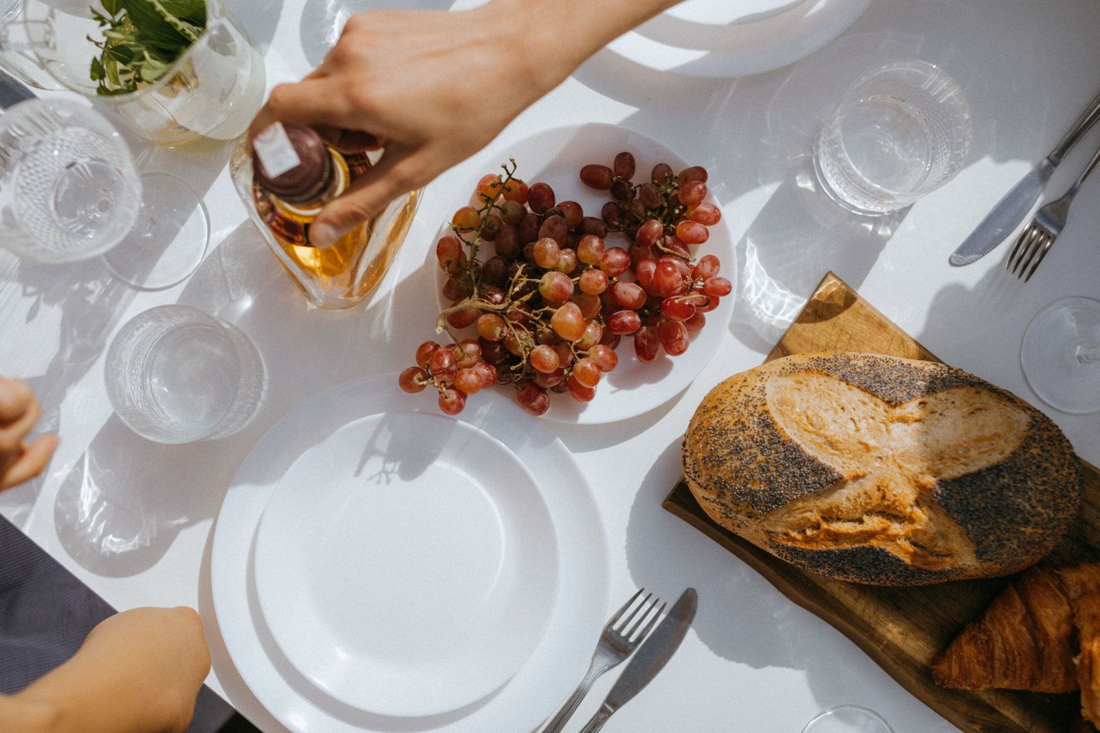 Seen from above: a table spread with bread, boards and small dishes, hands reaching in