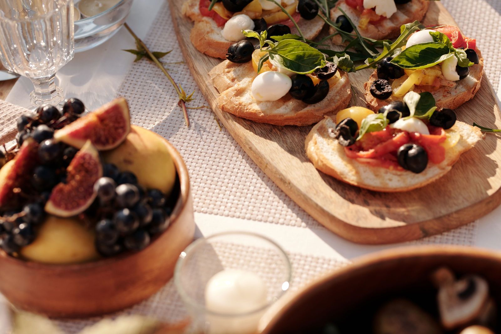 A sunlit outdoor table with bruschetta and small plates set down its length