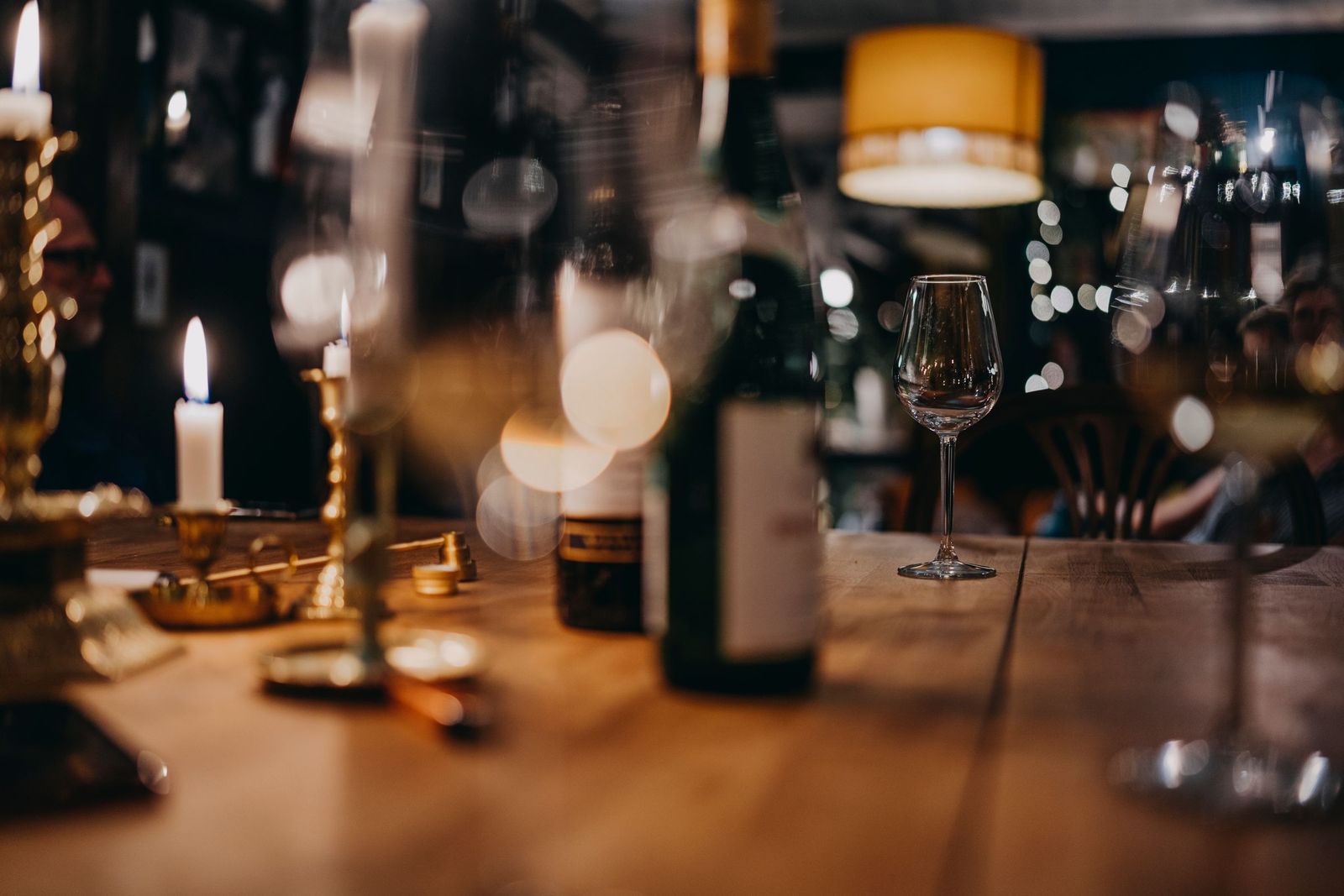 A candlelit table with wine glasses, a bottle and burning candles